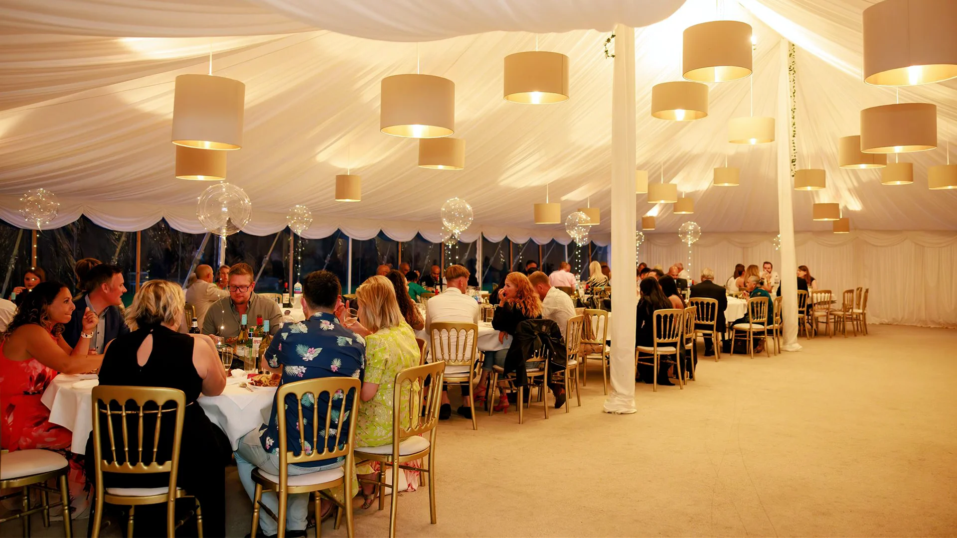 A breathtaking luxury reception featuring hanging floral installations and bespoke lighting inside a spectacular Marquee wedding venue Essex.
